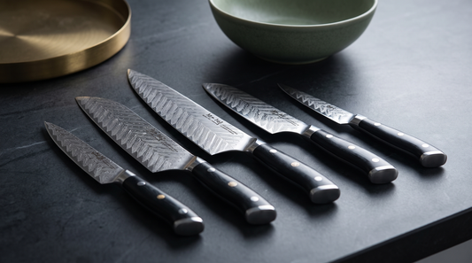 Riku Damascus VG10 knives laid in a row with daylight raking across the layered steel