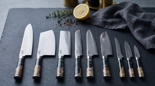 Japanese Damascus chef knives with black resin handles on a dark slate worktop